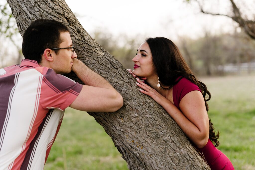spencer and dalia gaze at each other from two sides of a tree trunk
