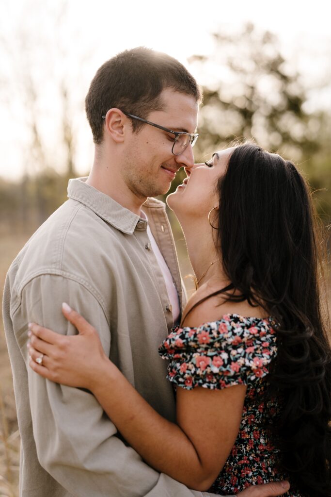 spencer and dalia smile as they lean in for a kiss while posing for their michigan engagement photographer